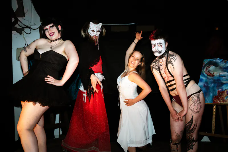Vier performers in kostuum die samen poseren