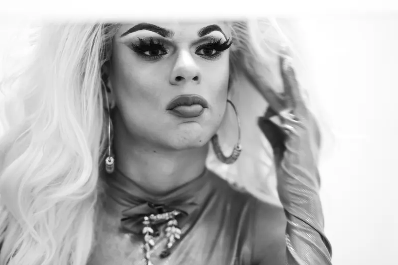 Drag queen met lang blond haar en creolen, zwart-wit