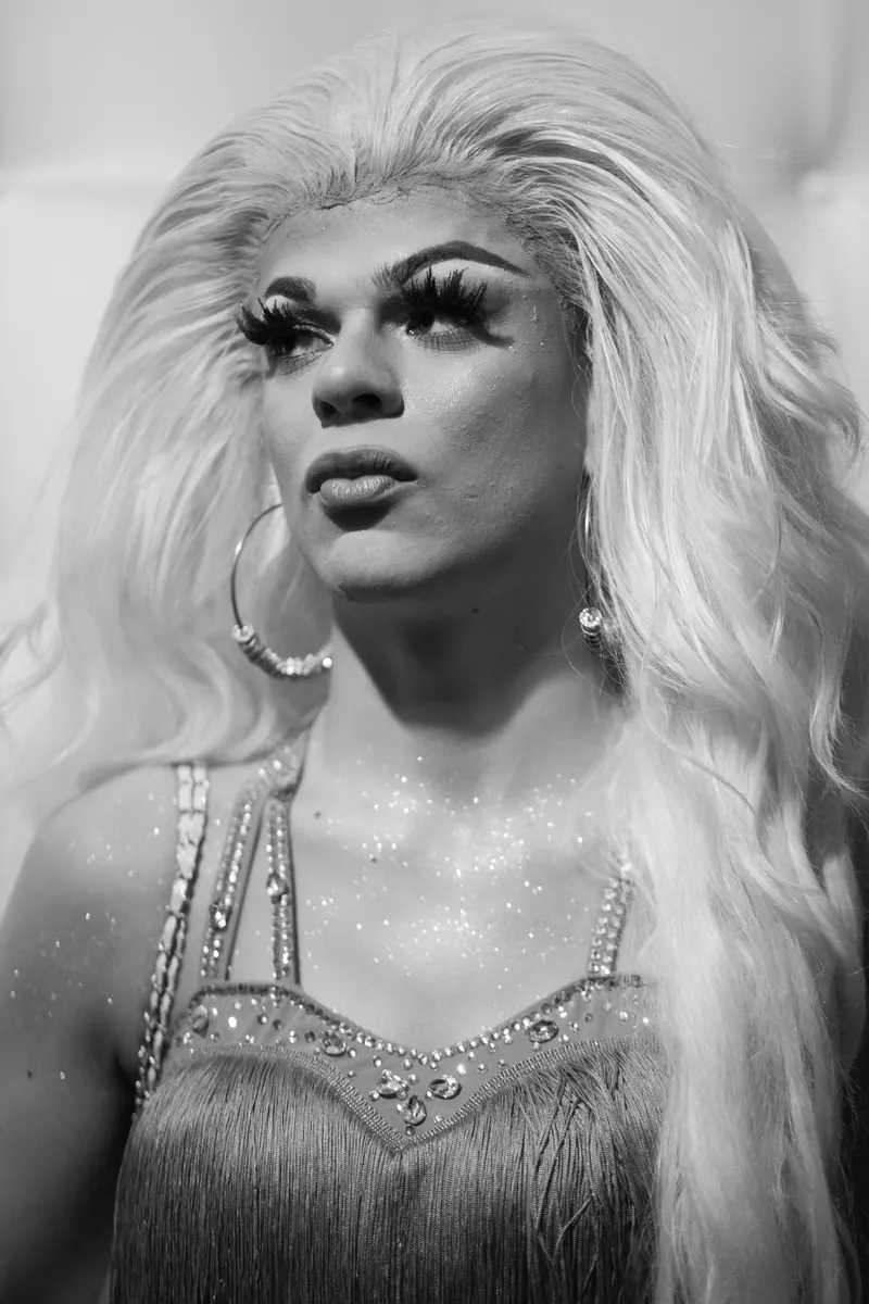 Drag queen in een glittertop die omhoog kijkt, zwart-wit