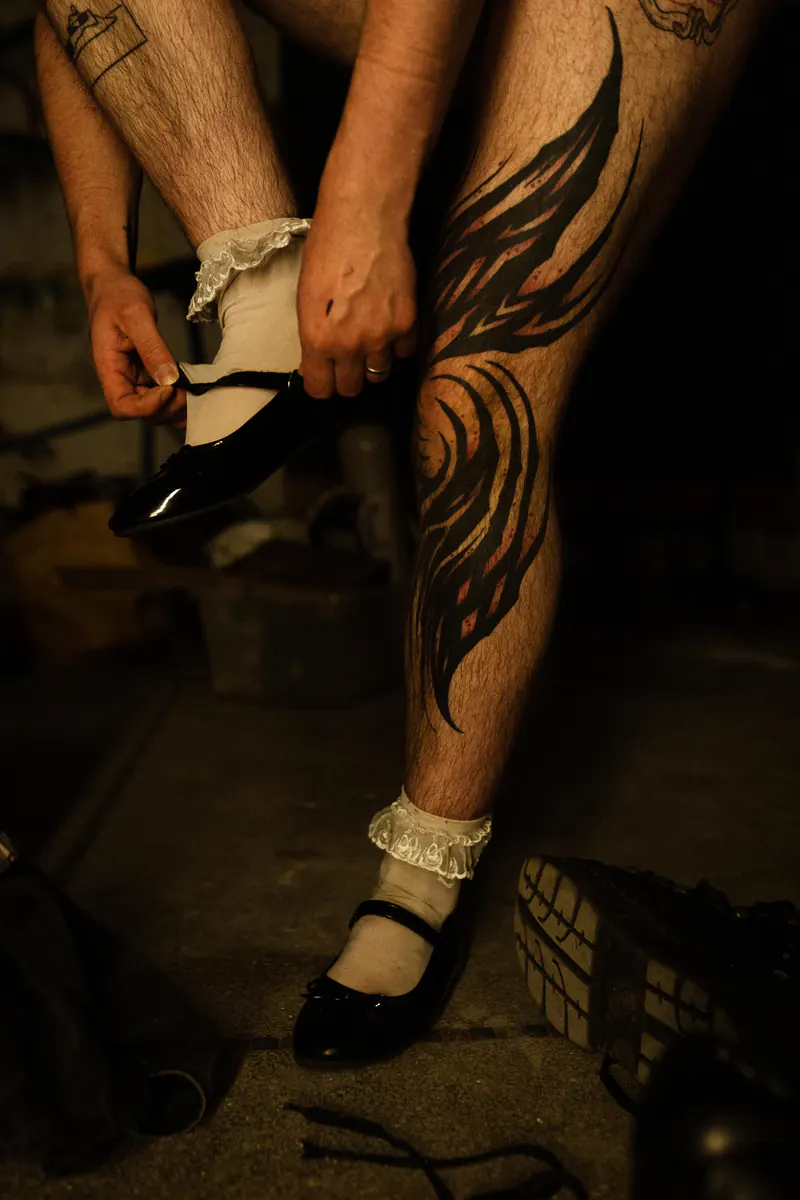 Getatoeëerde benen die kanten sokjes en zwarte hakken aantrekken