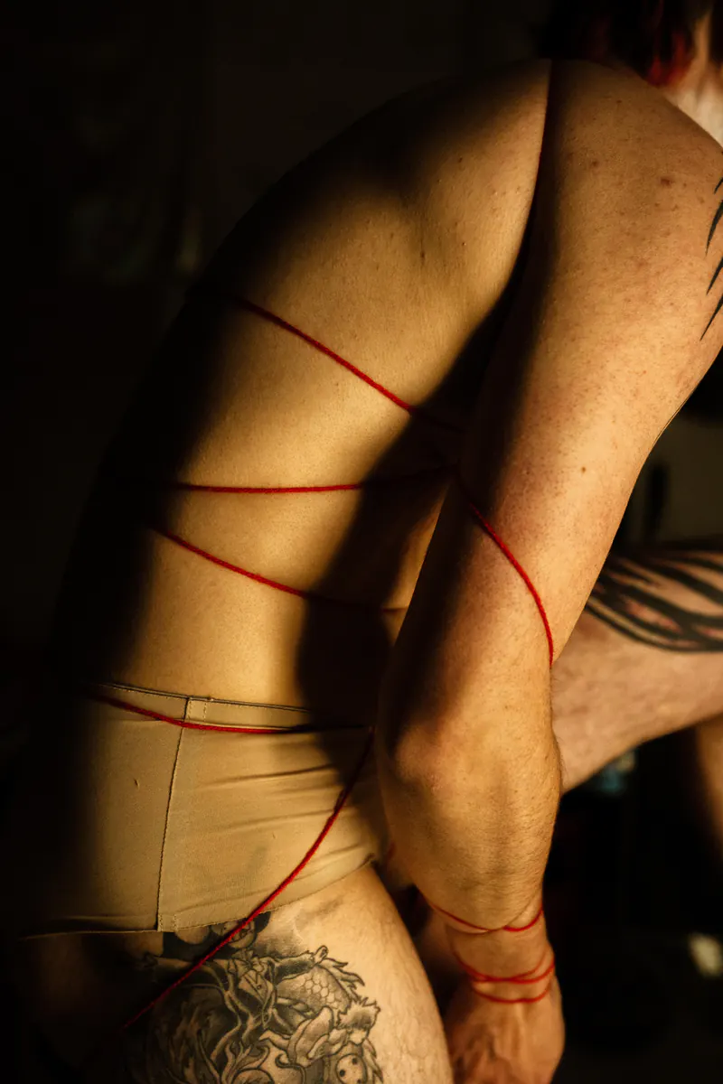 Getatoeëerd lichaam omwikkeld met rood touw